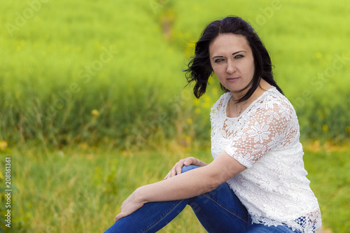 Beautiful young brunette in jeans takes a break from the bustle of the city photo