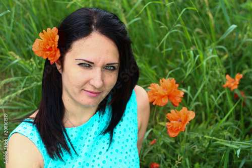 Beautiful young brunette resting in a meadow with wild poppies photo