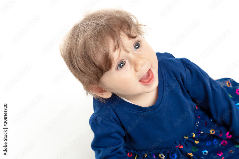 Portrait of happy baby girl 1 year old with blue eyes and dress posing in studio. White Background. Concept Happiness.
