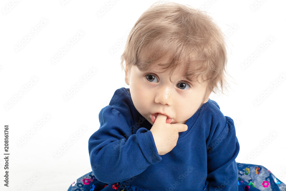 Portrait of happy baby girl 1 year old with blue eyes and dress posing in studio. White Background. Concept Happiness.