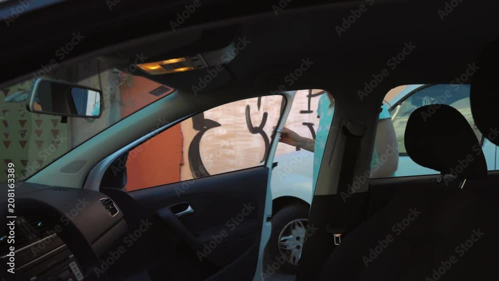 Woman put a jacket on the car seat and sits down on the driver's seat, intending to start the engine Woman put a jacket on the car seat and sits down on the driver's seat, intending to start the engine