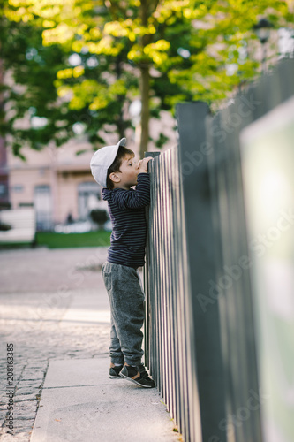 the child looks through the hole in the fence