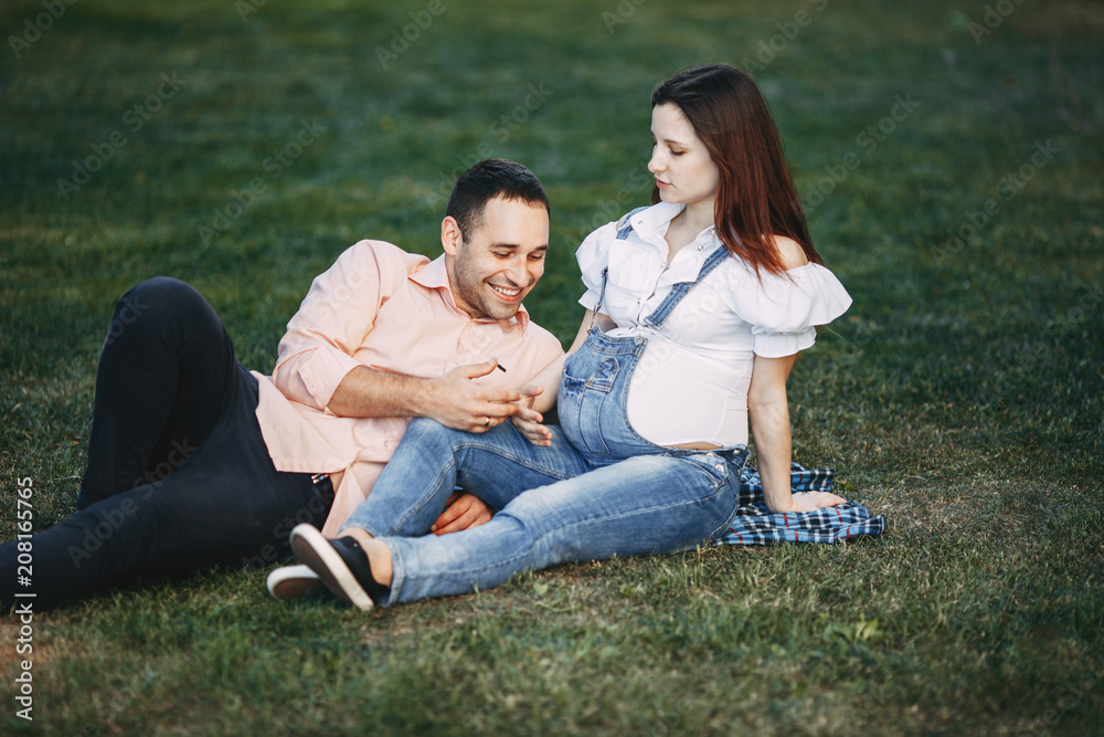 Pregnant couple sitting in the park chatting