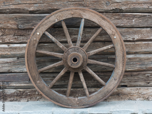 Antique wooden wheel of carriage isolated on an old wall © Whales Factory