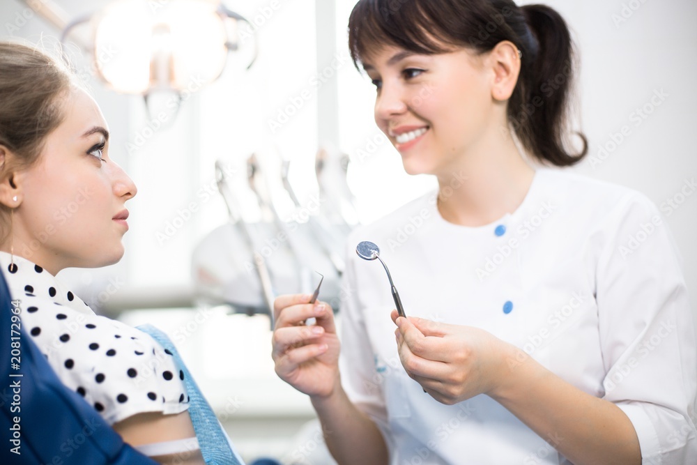 Dentist Talking to a Patient in a Dental Clinic Holding Tools Dentist Talking to a Patient in a Dental Clinic Holding Tools