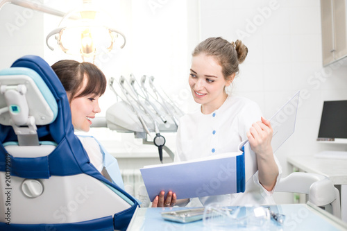 Woman Dentist Shows the Patient the Results of the Examination in the Dental Clinic
