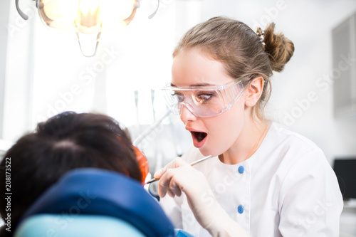 Surprised the Dentist with your Mouth Open. Treats the Teeth of the Patient in the Clinic