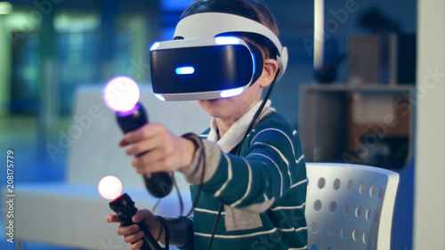 Little boy with virtual reality motion controllers having immersive gaming experience