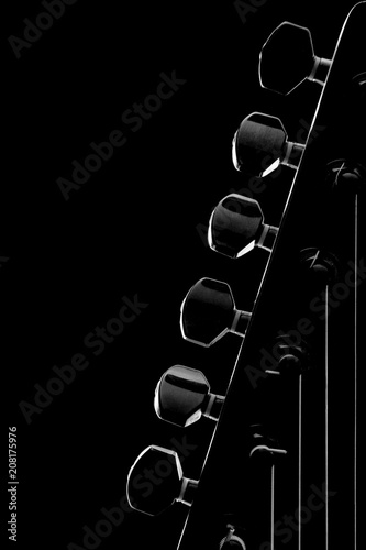 Foto Head of six string electric guitar closeup in low key isolated on black