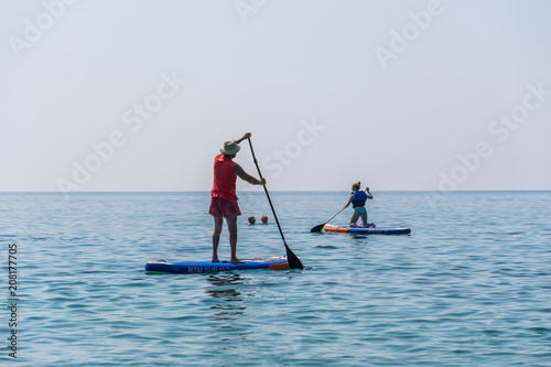 MONTENEGRO, BUDVA - JUNE 05/2017: tourists are engaged in rowing on the board (SUP) on the surface of the calm sea. © Sergej Ljashenko
