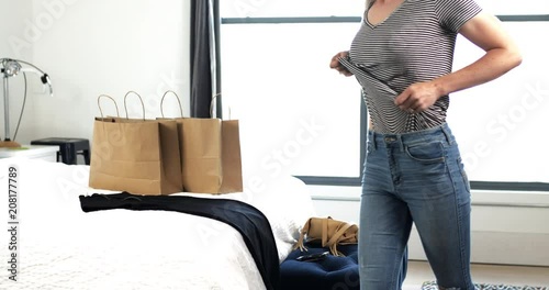 Attractive woman trying on new black dress, zipping up and heading out after shopping
