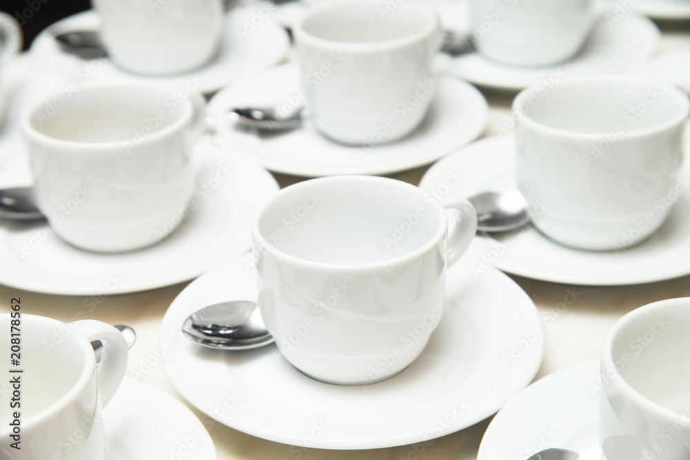 Many rows of white ceramic cup and saucer with teaspoon Many rows of white ceramic cup and saucer with teaspoon