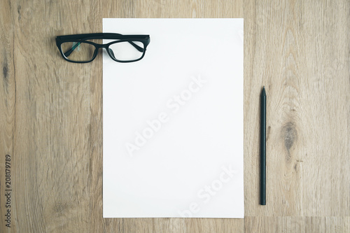 Blank paper on top of wood table with black pencil. © Windawake