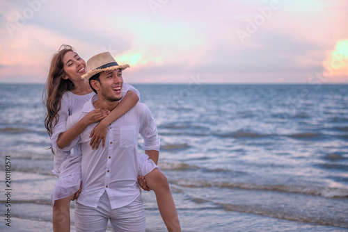 Happy young couple holding each other and laughing with enjoying together on the summer beach, romantic couple spending time concept.