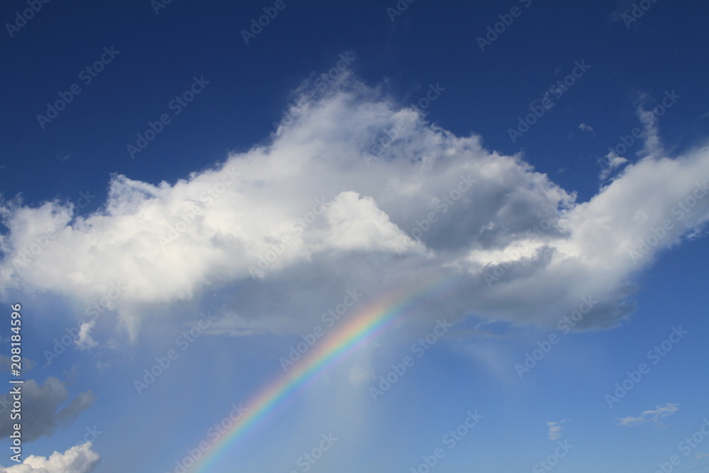 Rainbow through cloud with blue sky