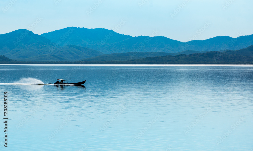 fisherman boat goes ahead at the sea coast against morning foggy