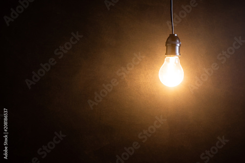 Brightness tungsten light bulb hanging at dark room