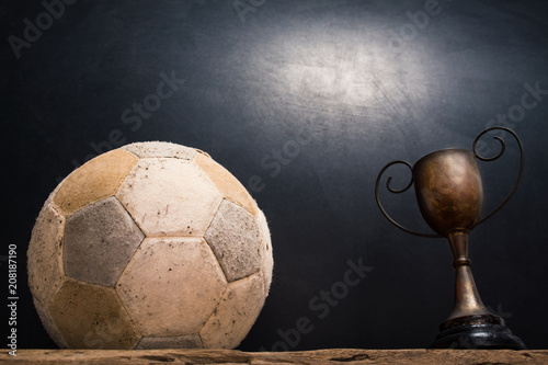 still life photography : old football and vintage trophy on old wood table in championship concept