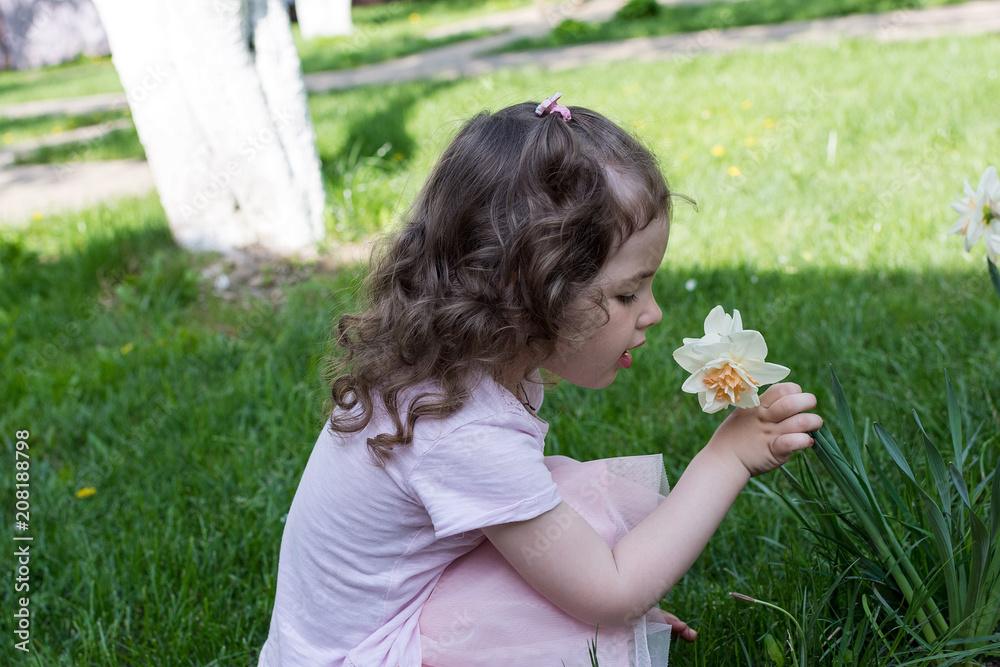 Little girl smell narcissus flower at spring time