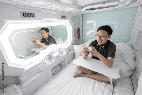 man using smartphone in the capsule hotel. photo