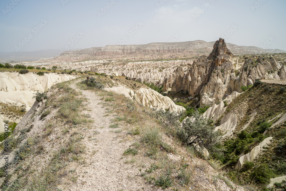 Walking trail through beautiful inspiring scenic panoramic stone mountain landscape view of red valley with sky background, Cappadocia