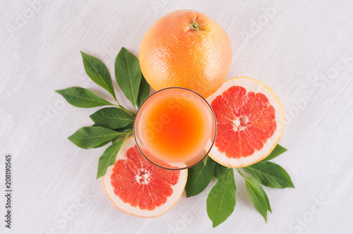 Summer bright fresh pink cocktail of grapefruits with green leaves, slice grapefruit on white wooden background, top view.