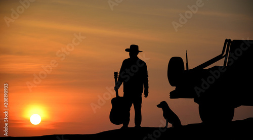 Man he is watching The sun is falling Beside the car and dog hold the guitar