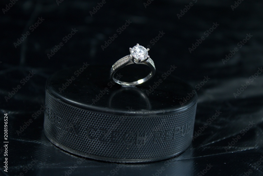 Naklejka premium Engagement Ring on hockey puck with the inscription `Czech Republic` on the SILVER background.Black puck with Engagement Ring on SILVER background. Will you marry me?