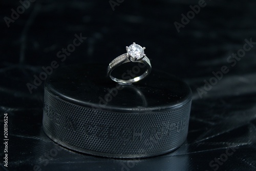 Engagement Ring on hockey puck with the inscription `Czech Republic` on the SILVER background.Black puck with Engagement Ring on SILVER background. Will you marry me?