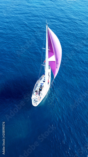 Aerial drone bird's eye view of beautiful purple sail boat cruising in deep blue ocean