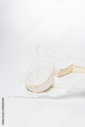 close-up shot of brie cheese on crumpled paper and on white surface