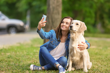Young woman taking selfie together with her dog in park. Pet care