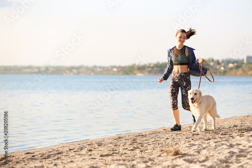 Young woman with her dog together on beach. Pet care