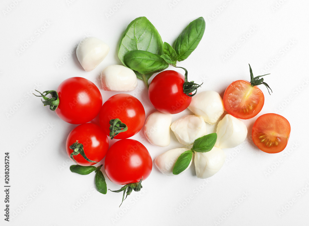 Ripe red tomatoes, mozzarella cheese balls and basil on white background, top view Ripe red tomatoes, mozzarella cheese balls and basil on white background, top view