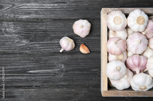Crate with fresh garlic bulbs on wooden background, top view