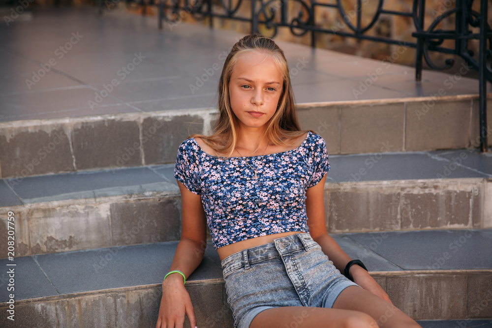 teenage female dressed in jeans sits on stairs