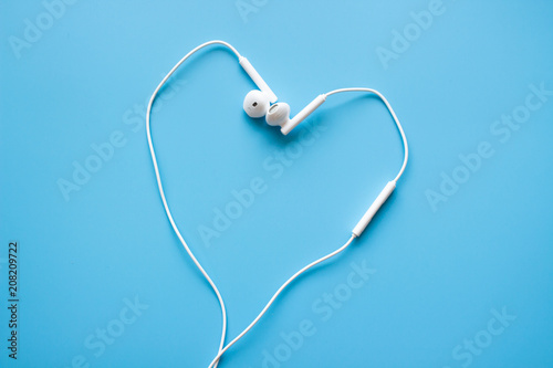Earphone for smartphone heart shape on blue background with copy space. Love music concept