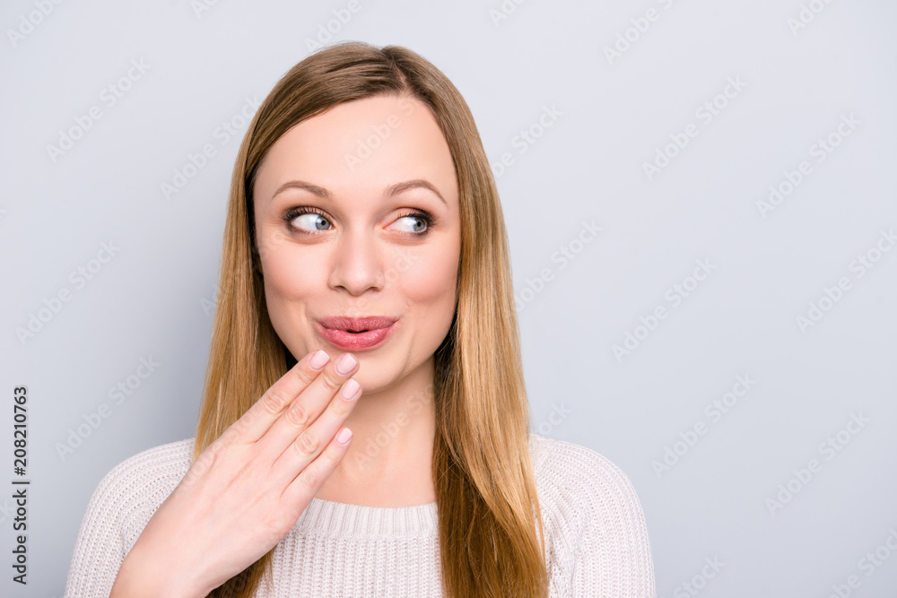 Oops! Portrait of funny cheerful girl holding palm near pout lips looking at copy space empty place with eyes isolated on grey background Oops! Portrait of funny cheerful girl holding palm near pout lips looking at copy space empty place with eyes isolated on grey background