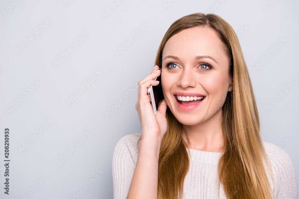 Portrait with copy space empty place of cheerful glad girl speaking on phone with lover using smart phone looking away isolated on grey background Portrait with copy space empty place of cheerful glad girl speaking on phone with lover using smart phone looking away isolated on grey background
