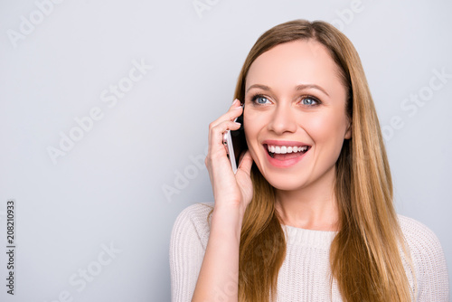 Portrait with copy space empty place of cheerful glad girl speaking on phone with lover using smart phone looking away isolated on grey background