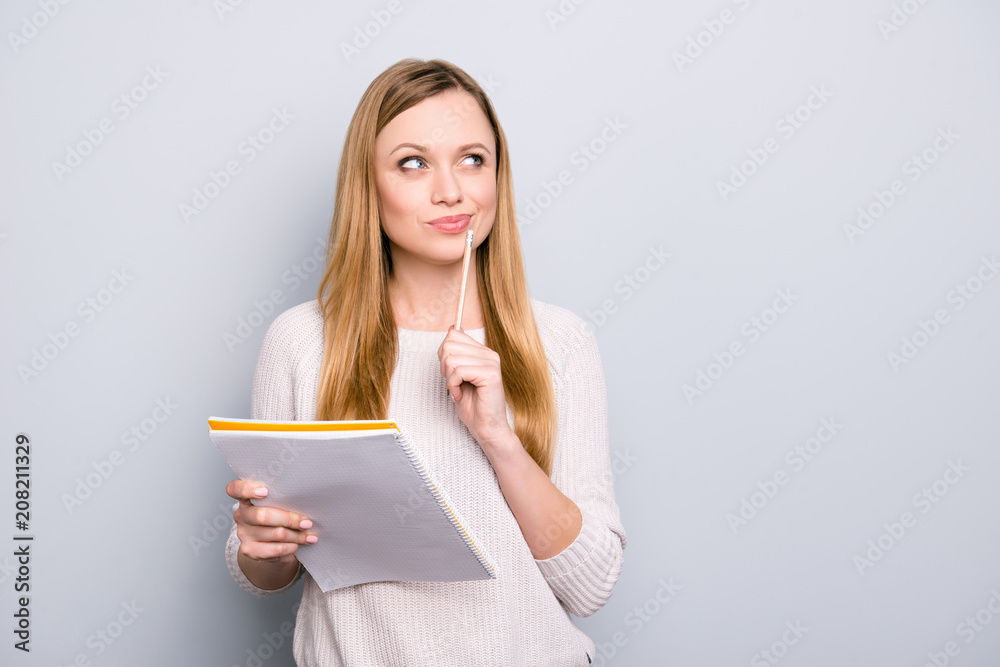 Portrait with copy space empty place of thoughtful pensive girl having copybook and pen in hands looking up, writer waiting for muse, isolated on grey background Portrait with copy space empty place of thoughtful pensive girl having copybook and pen in hands looking up, writer waiting for muse, isolated on grey background