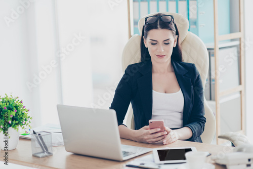 Cropped portrait of trendy stylish woman holding smart phone having rest time out chatting with friends checking email using wifi 5G internet sitting at desk in workstation