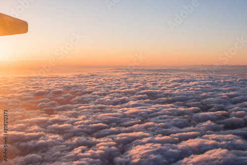 Evening sunset sky from the window of the airplane. View of the beautiful sky and clouds from the window of the airplane. Wing of an airplane against a beautiful sunset sky.