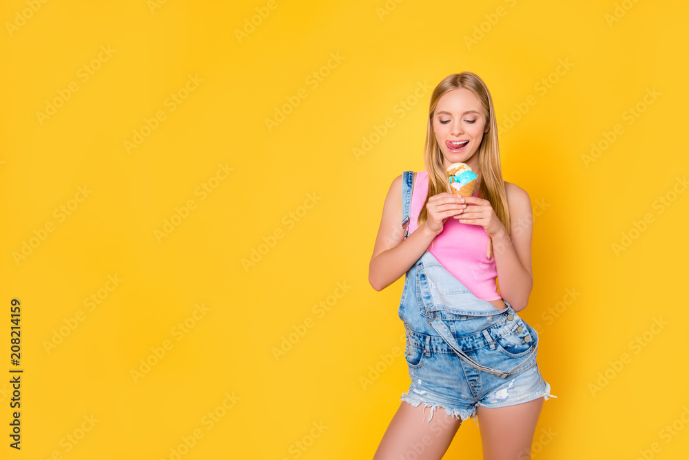 Portrait of tempting sexy girl licking her upper lip looking at vanilla caramel ice cream in waffle cone in hands isolated on yellow background, good summer vibes only concept Portrait of tempting sexy girl licking her upper lip looking at vanilla caramel ice cream in waffle cone in hands isolated on yellow background, good summer vibes only concept