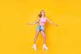 Portrait of glad professional girl riding on roller skates enjoying wind flow fresh air isolated on yellow background, sporty fit athletic active people concept