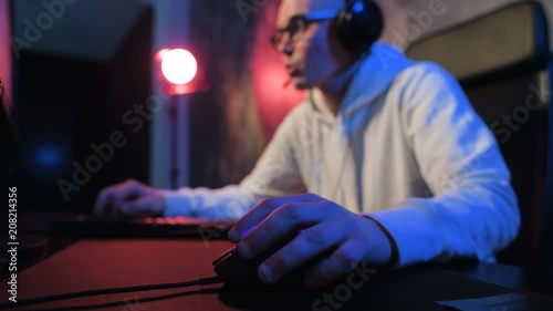 Close-up addiction guy with manly hands playing video game on computer screen with fingers on keyboard. Selective focus on a hand with mouse photo