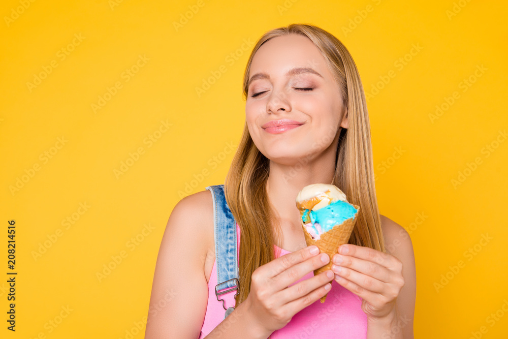 Portrait of cheerful cute lover having vanilla caramel ice cream scoops in hands keeping eyes closed enjoying taste smell aroma isolated on bright vivid yellow background Portrait of cheerful cute lover having vanilla caramel ice cream scoops in hands keeping eyes closed enjoying taste smell aroma isolated on bright vivid yellow background