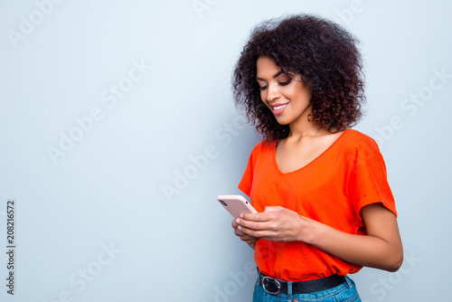 Portrait with copy-space of busy charming woman with modern hairdo in bright outfit holding smart phone in hands using wifi 5G internet checking email searching contact isolated on grey background