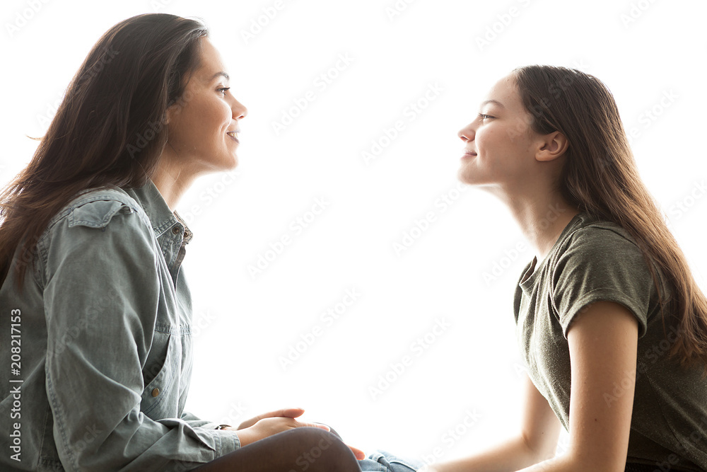 Two sisters playing with each other and having a great time together over white background Two sisters playing with each other and having a great time together over white background