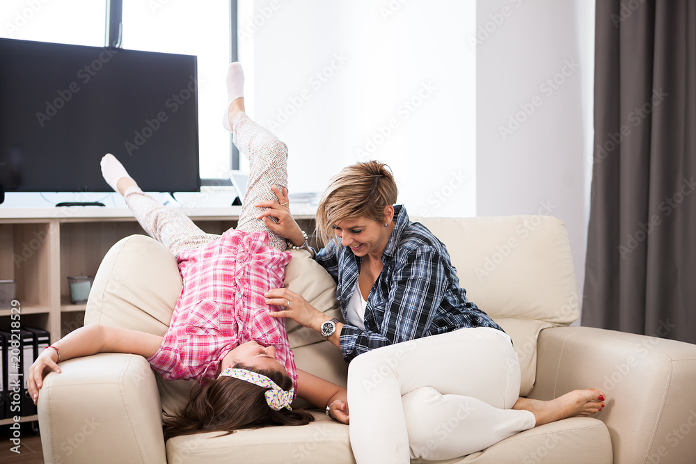 Middle aged woman on the couch with her teenage daughter in the living room Middle aged woman on the couch with her teenage daughter in the living room